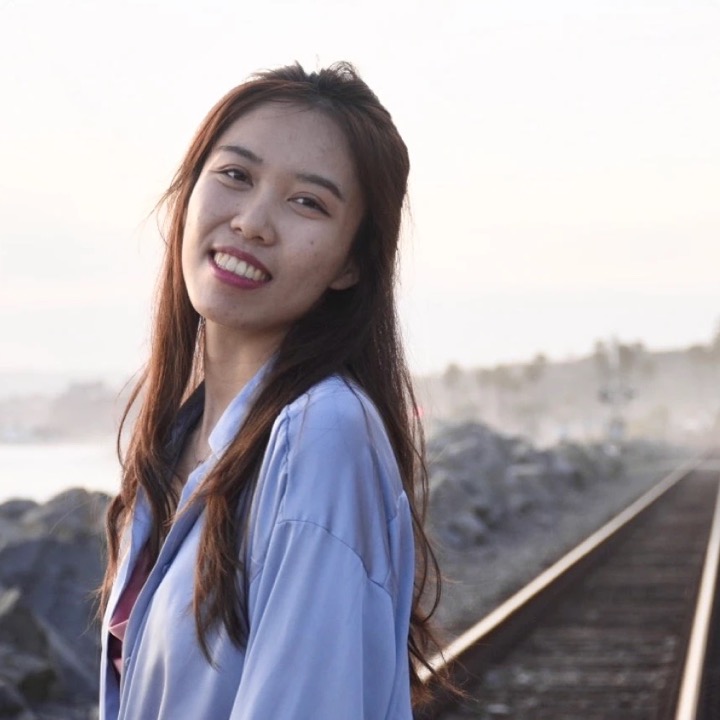 Charlene smiling beside train tracks on the coast